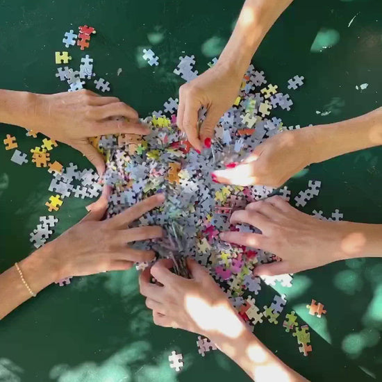 three pairs of hands muddling with a heap of puzzle pieces unfolding it into a finished puzzle