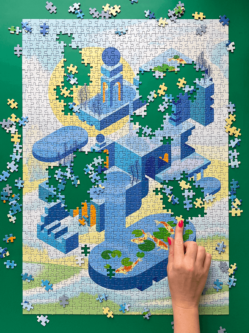 Auf grünem Hintergrund liegt ein halbfertiges "Water Falls" Puzzle, diverse Teile sind verteilt und von unten kommt eine Hand mit pinken Nägeln ins Bild und legt ein gelbes Puzzleteil.