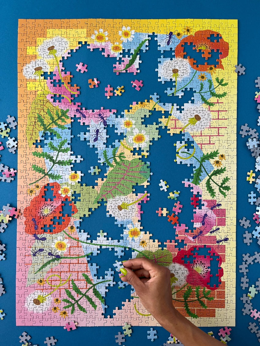 A half-finished puzzle on blue background, a hand comes into the frame to place another piece